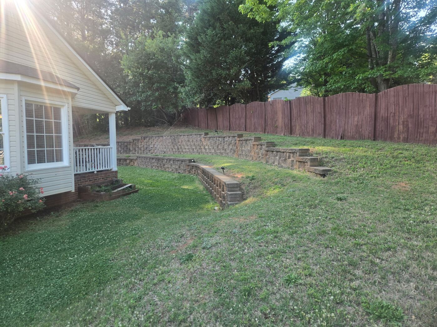 Tiered wood retaining wall in a backyard with healthy grass — the kind of property structure LawnSkapers crews know and treat