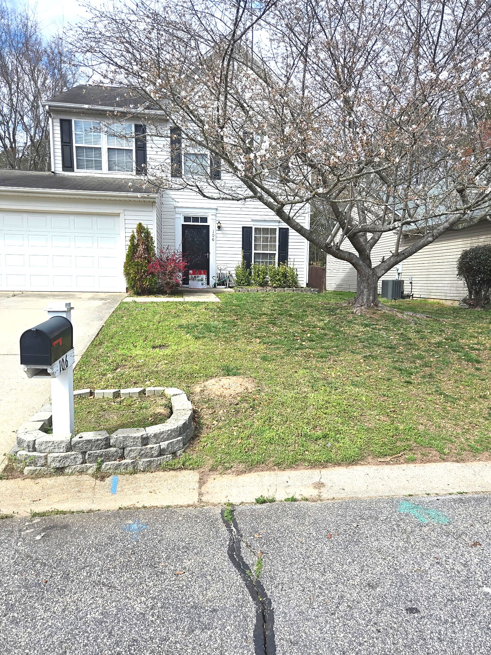 Front yard with stone wall and mailbox before lawn care