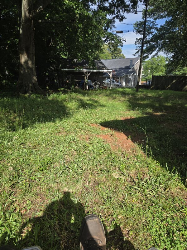 Wide-angle view of overgrown yard before LawnSkapers mowing service in Simpsonville